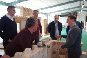 Gesprächsrunde an aufgebauten Holzbausteinen Mehrere Personen stehen um einen Aufbau aus Holzbausteinen und diskutieren.