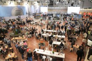 Messehalle mit Besuchern und Ausstellerständen Blick von oben in eine Messehalle mit vielen Besuchern, Ständen und Sitzbereichen.