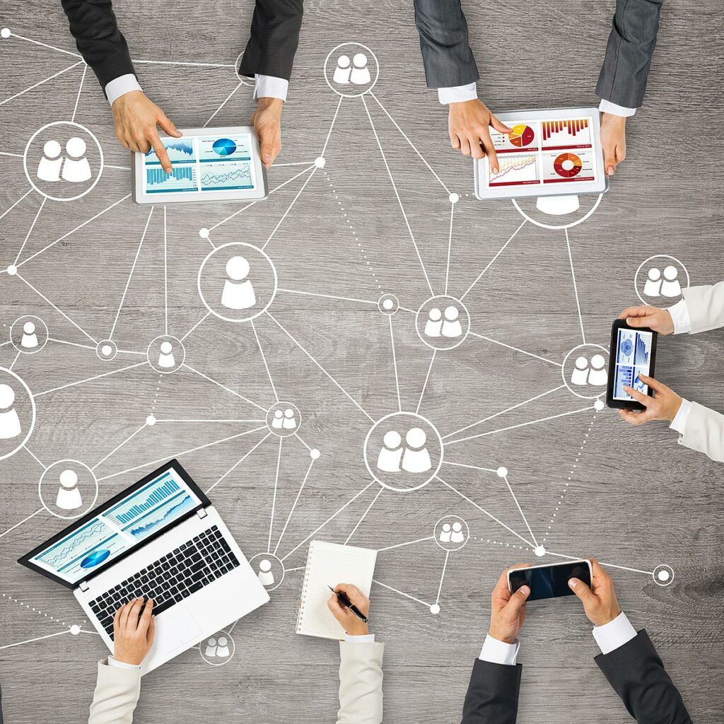 Mehrere Personen arbeiten mit Laptop, Tablet und Smartphone; darüber liegt eine Grafik mit vernetzten Personen-Symbolen.